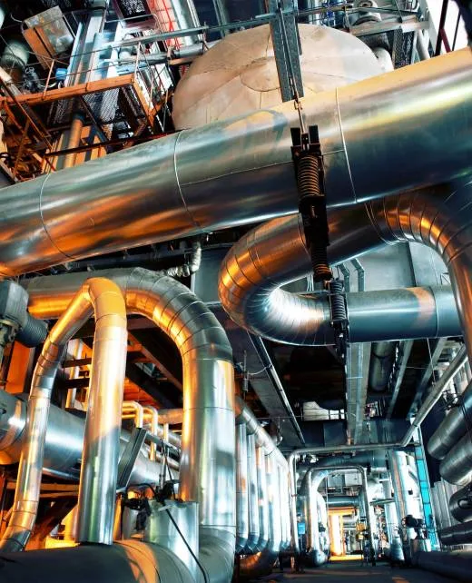 Vue intérieure d’une installation industrielle EIDF avec un réseau complexe de tuyaux et conduits métalliques en acier inoxydable, comprenant vannes, réservoirs et structures de support pour le transport de fluides et gaz.EIDF : Fabricant de gaines de ventilation Sartrouville